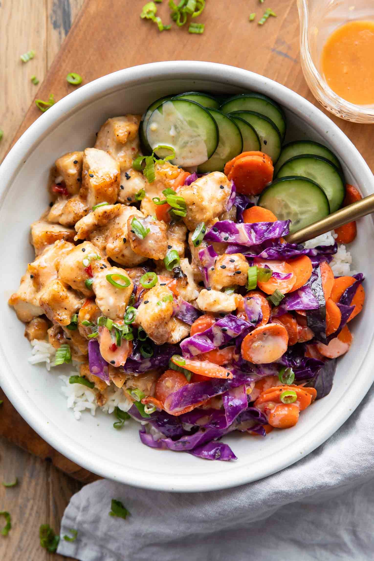 Crispy Bang Bang chicken bowl with vibrant fresh toppings and a drizzle of sauce