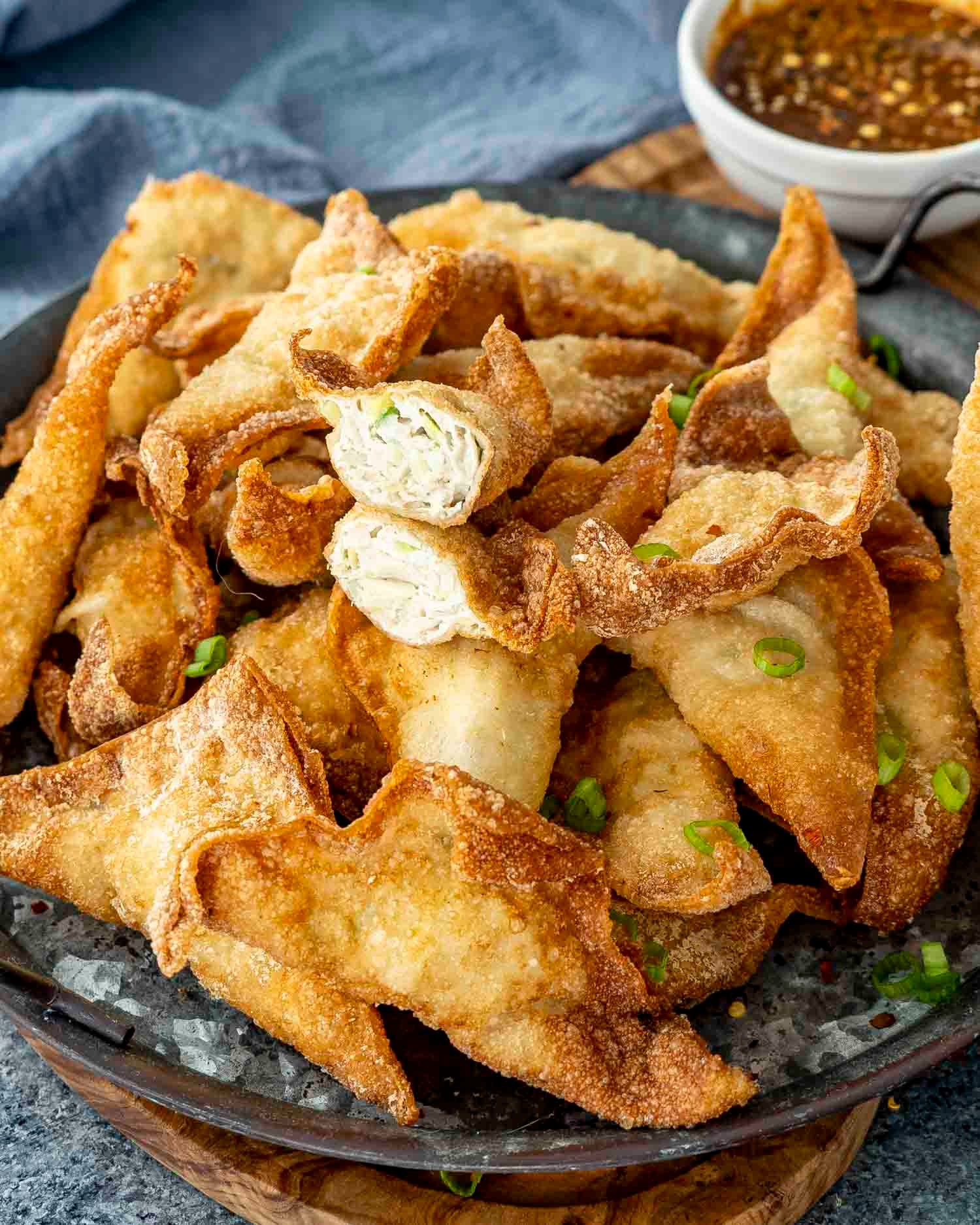 Platter of golden brown crispy chicken wontons with a small bowl of dipping sauce