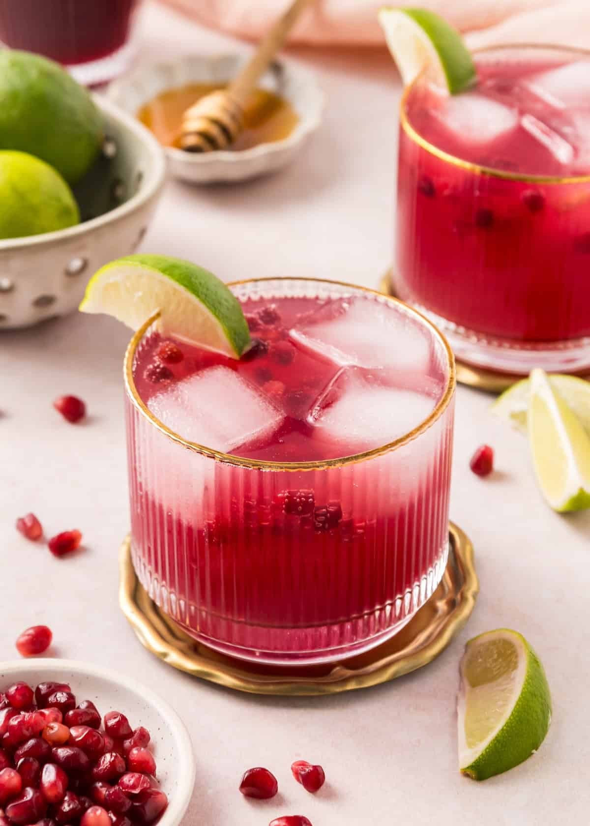 Vibrant sparkling pomegranate mocktail in a festive glass with rosemary and lime garnish, holiday setting