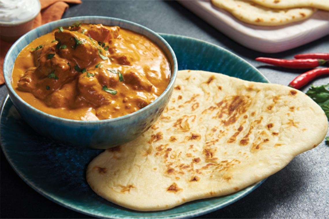 homemade butter chicken dish served with naan bread