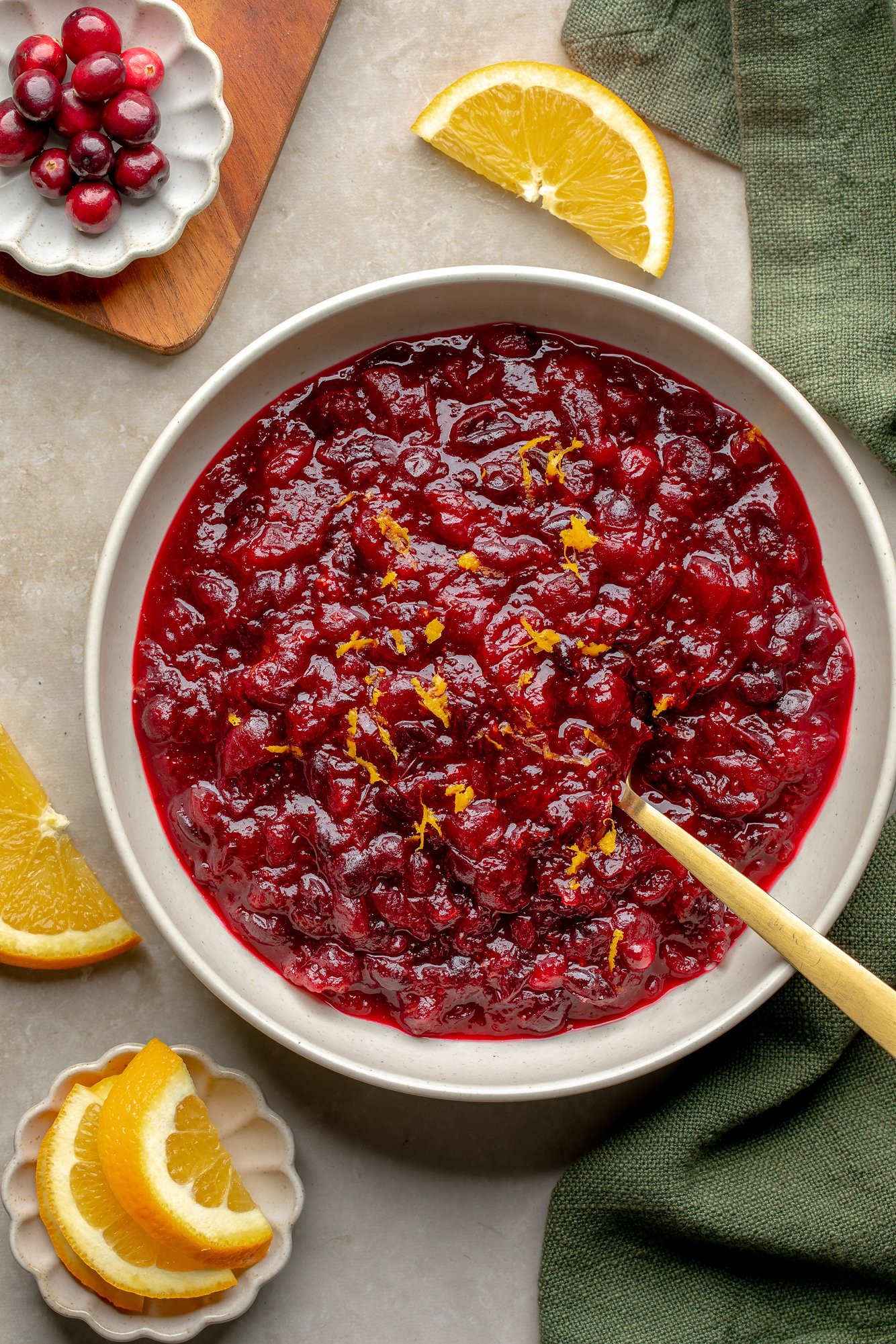Homemade cranberry sauce with fresh orange zest in a serving bowl, garnished with orange slices and cranberries
