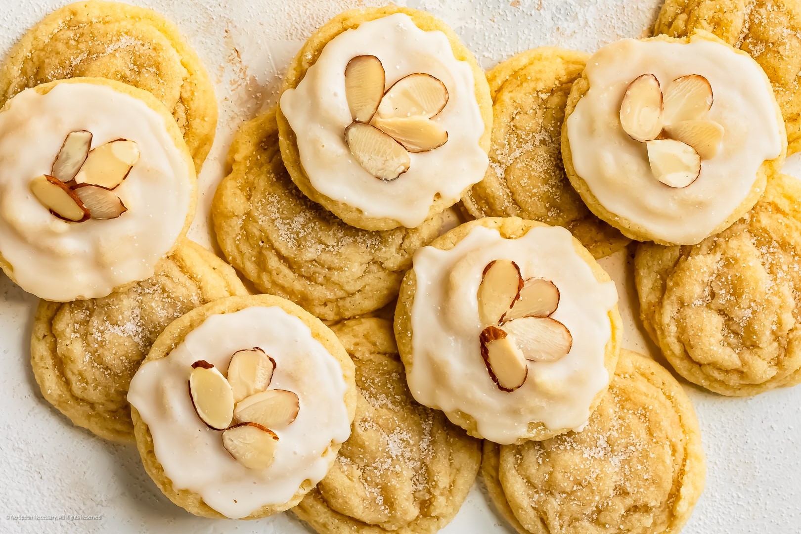 Plate of golden almond cookies with crisp edges, cozy kitchen background, soft lighting