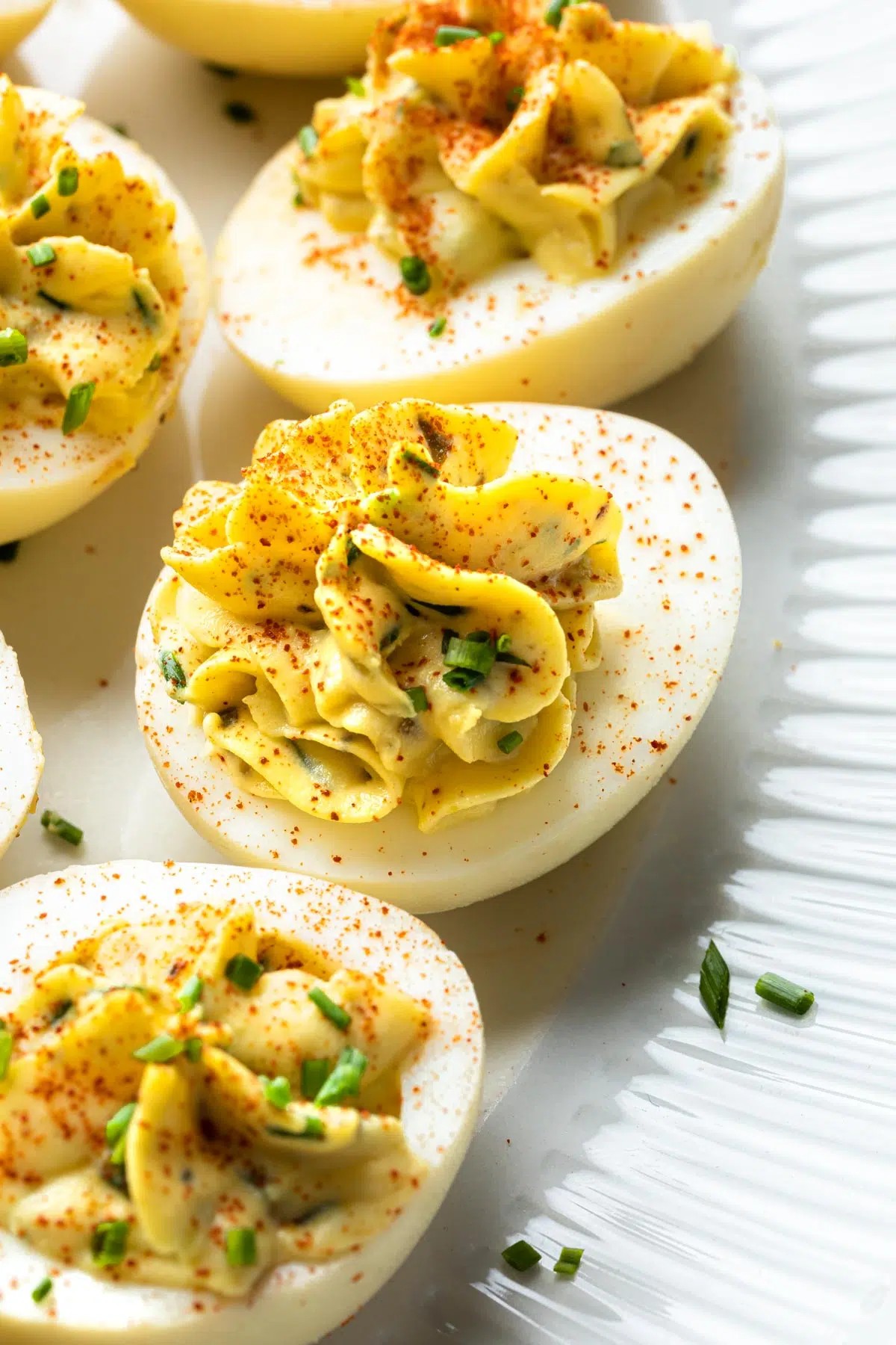 platter of deviled eggs garnished with smoked paprika and fresh chives, close-up, natural lighting