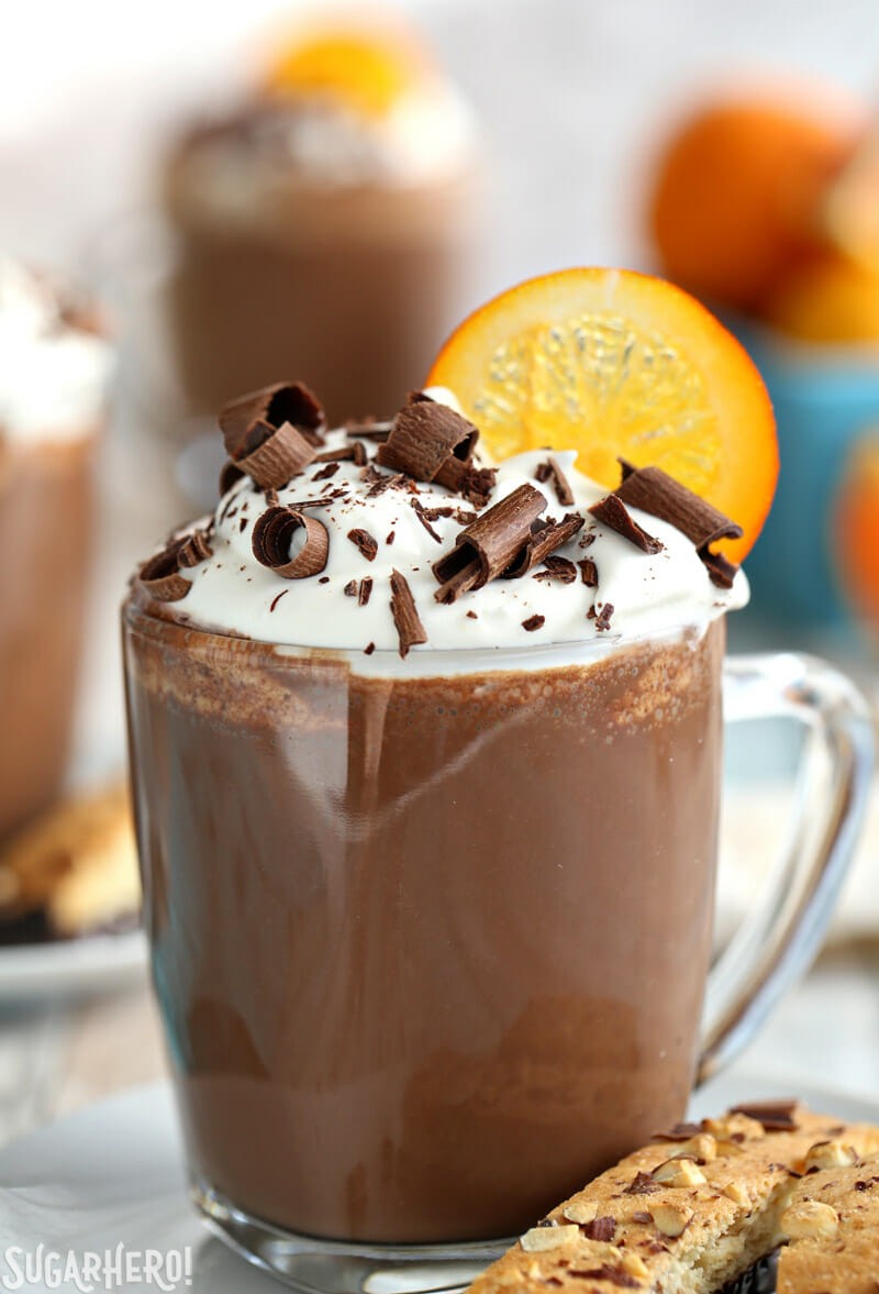 Gourmet orange hot chocolate with whipped cream, chocolate shavings, and candied orange peel in an elegant mug, cozy setting