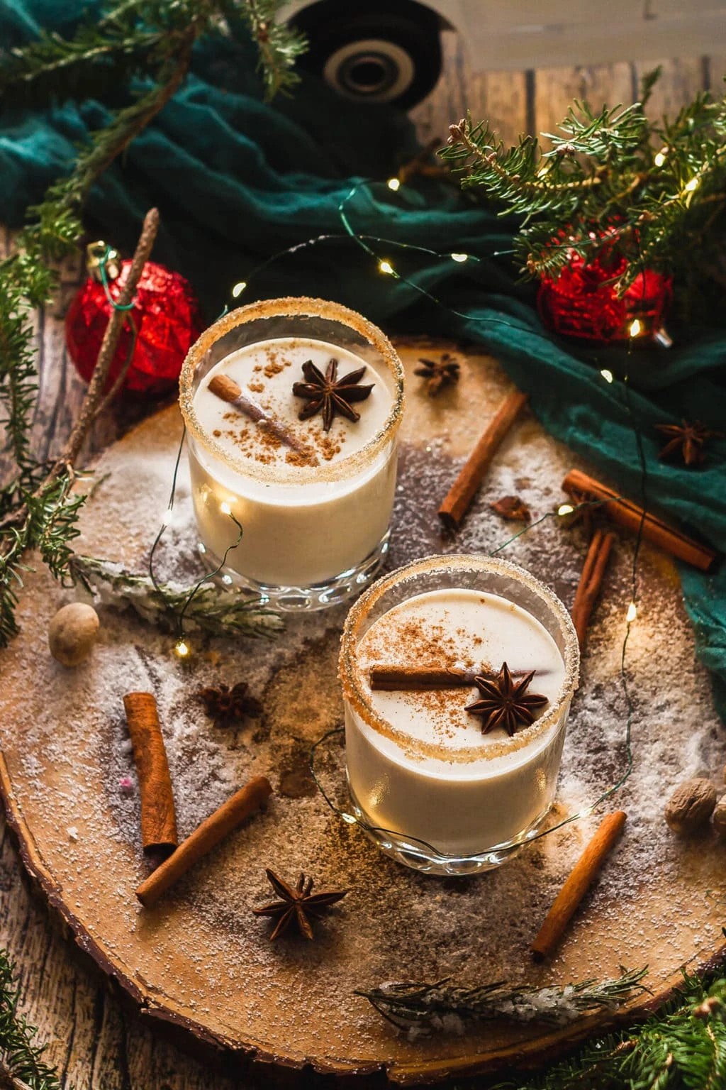 festive coquito drink in a beautiful glass, garnished with cinnamon stick and grated nutmeg on a wooden table with holiday decorations