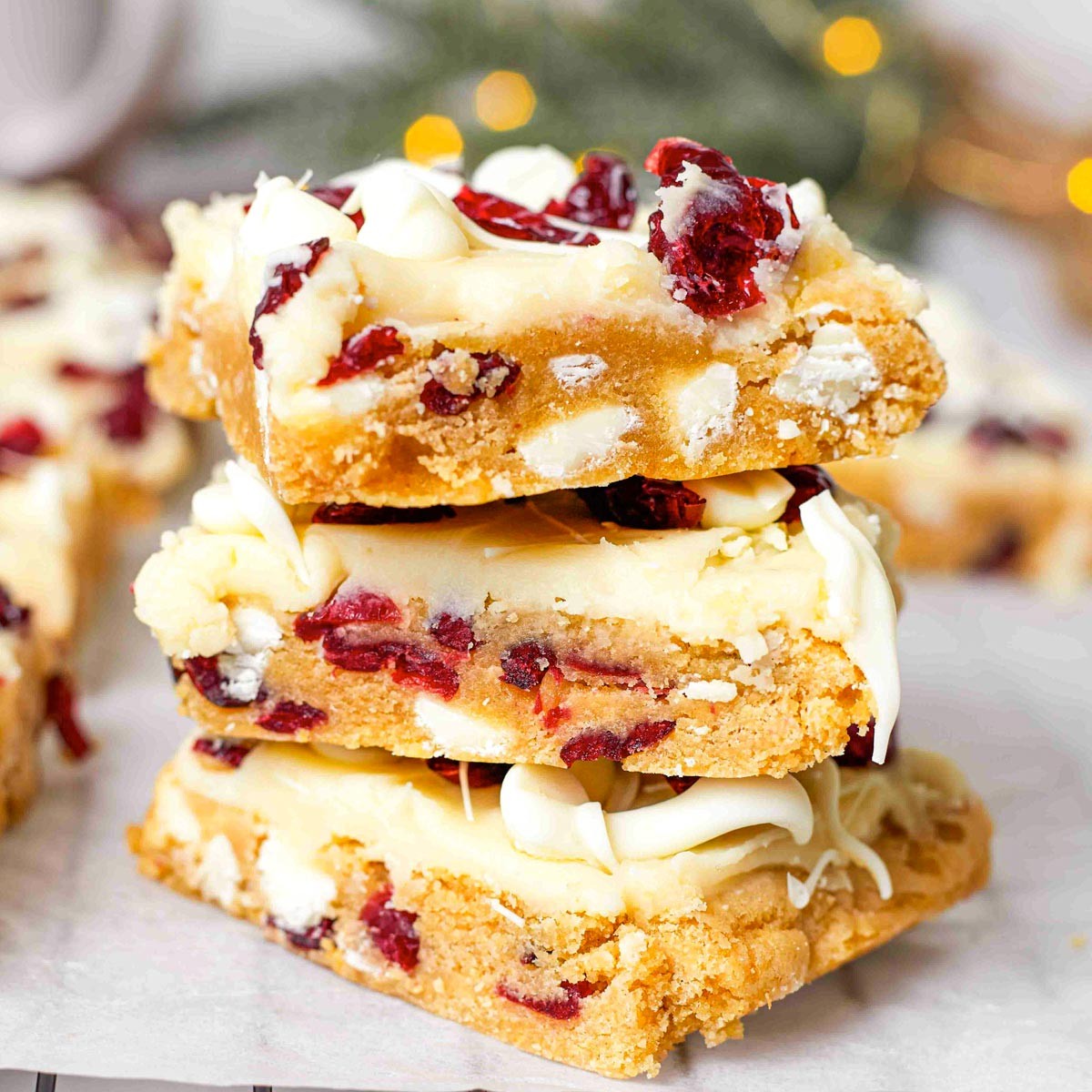Festive cranberry bliss bars with white chocolate drizzle on a rustic wooden table, cozy holiday atmosphere