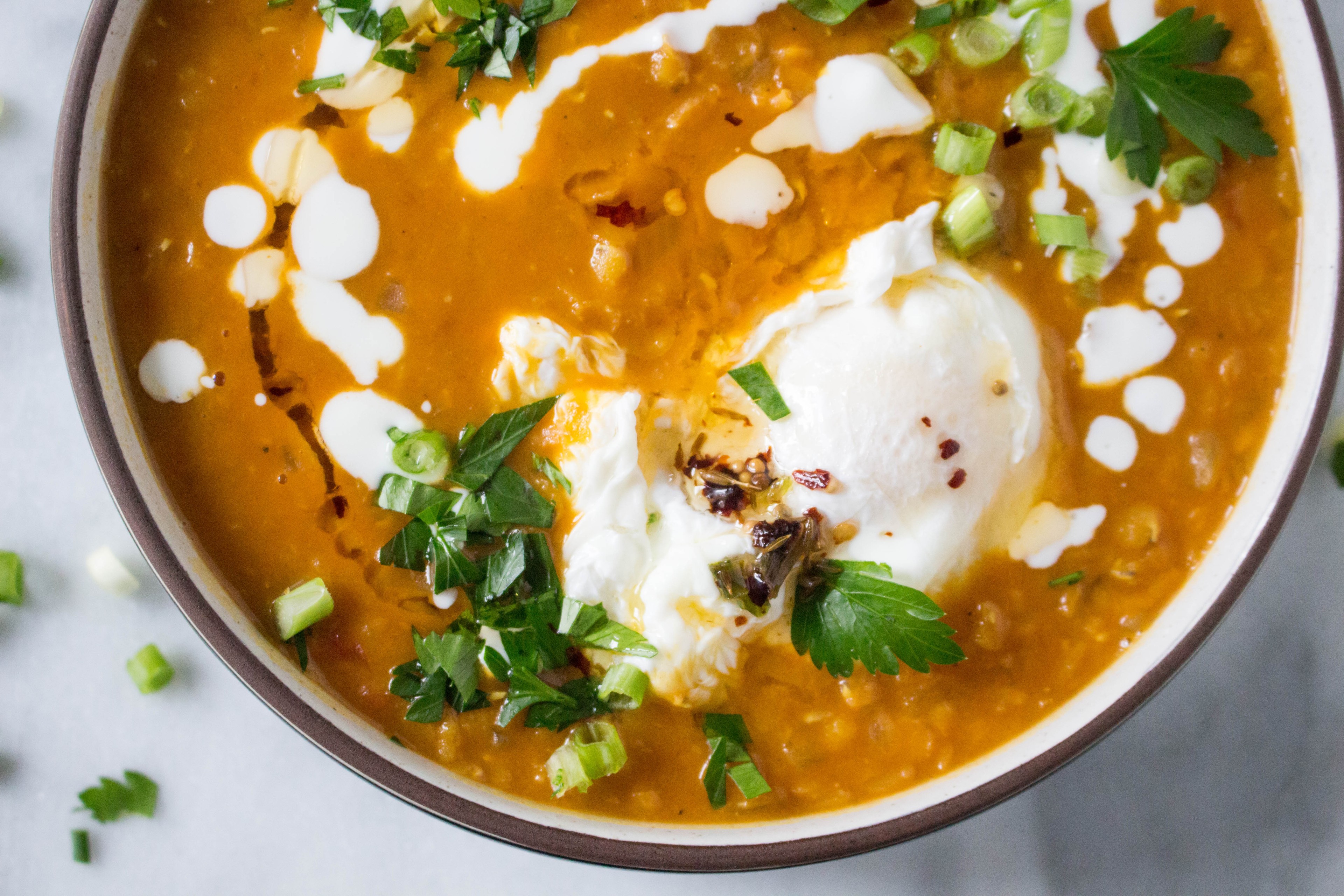 a vibrant lentil soup protein bowl topped with fresh herbs and a poached egg