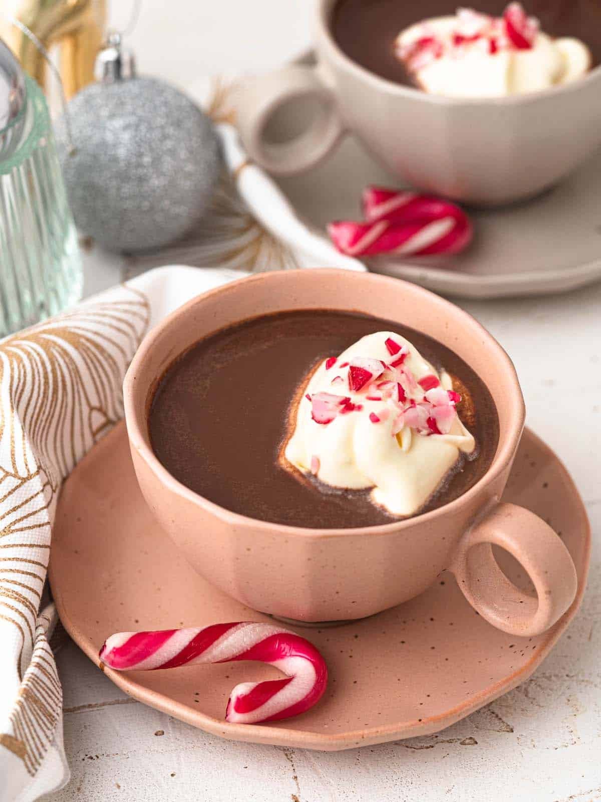 steaming mug of peppermint hot chocolate with whipped cream and candy canes