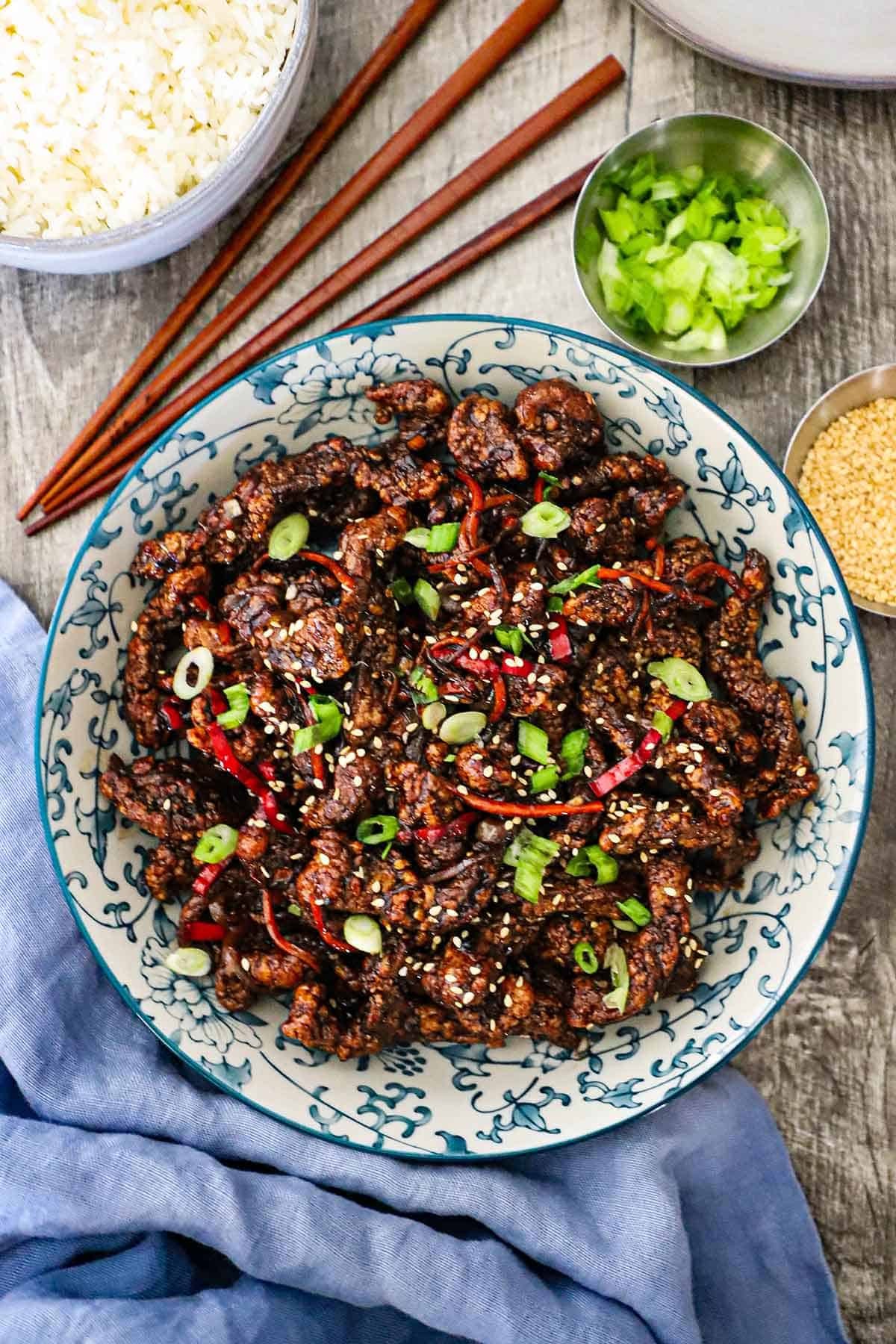 overhead shot of chili-glazed beef bowls with rice and green onions, vibrant, homemade