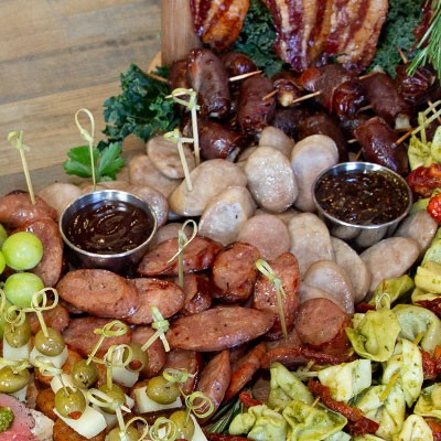 Maple glazed sausage balls on a rustic wooden board with a drizzle of maple syrup and fresh herbs