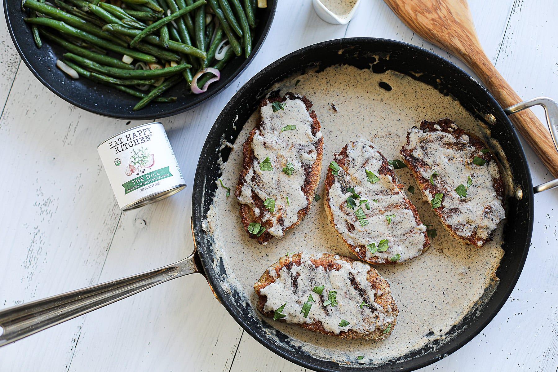 pan-seared pork chops topped with creamy dill sauce and fresh dill garnish